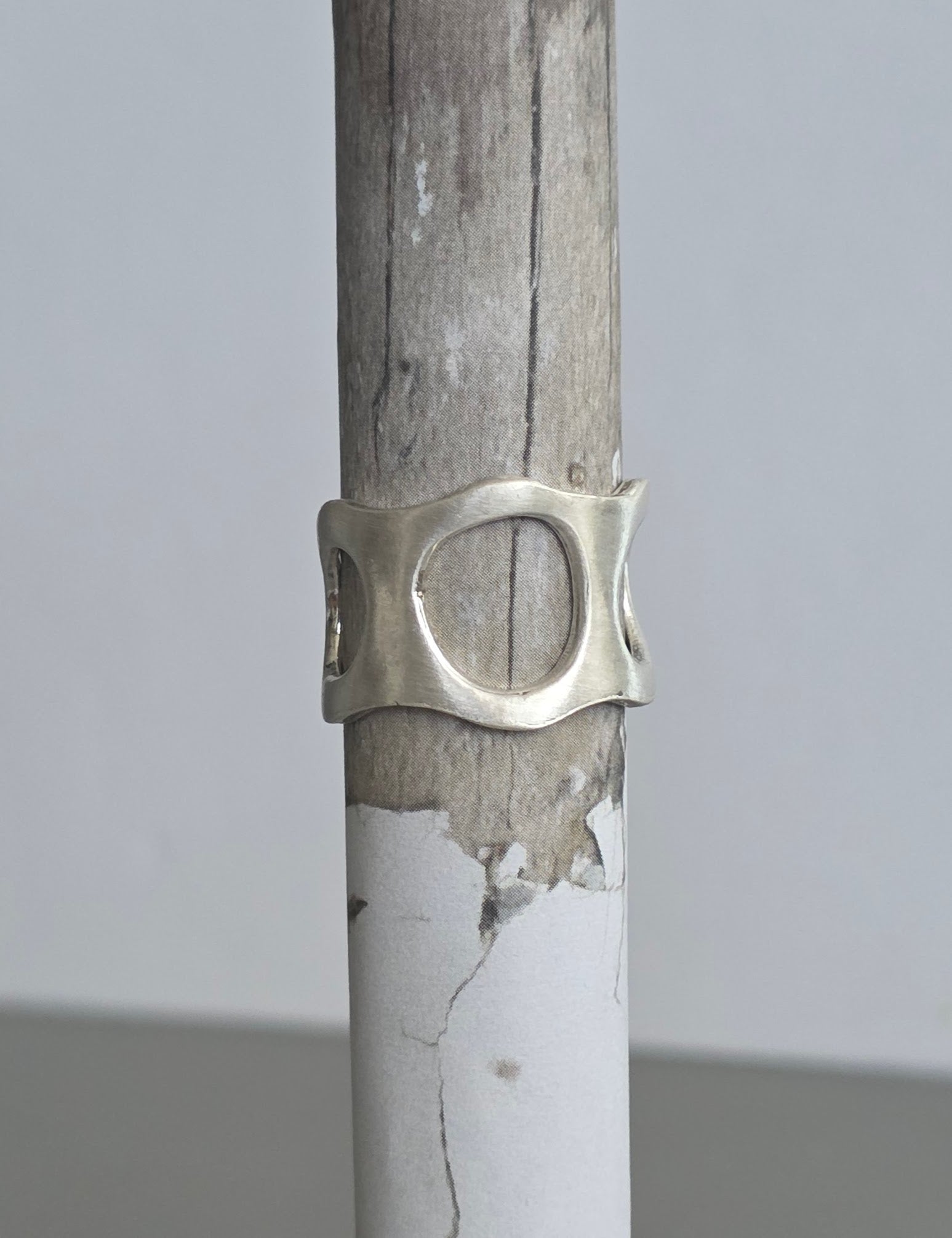 Silver ring on a wooden stick against a gray background