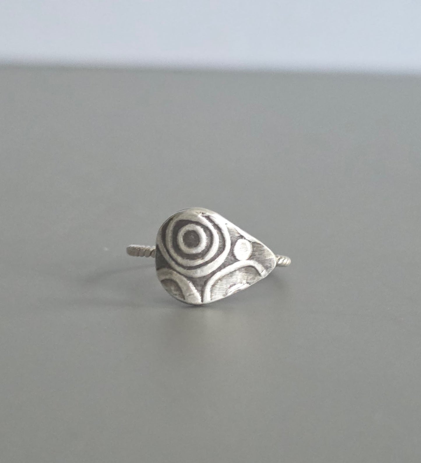 Silver ring with a unique design on a gray background