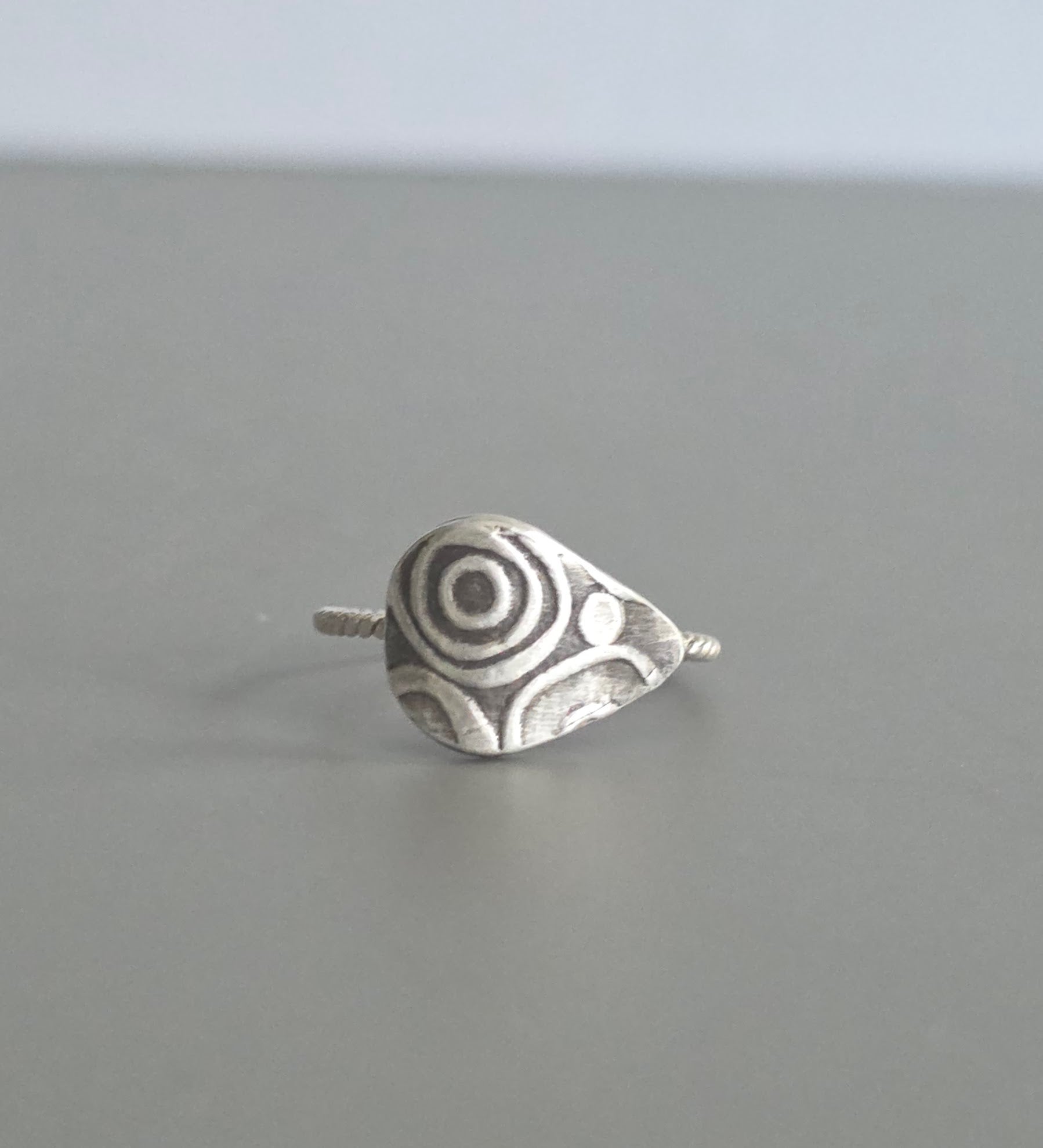 Silver ring with a unique design on a gray background