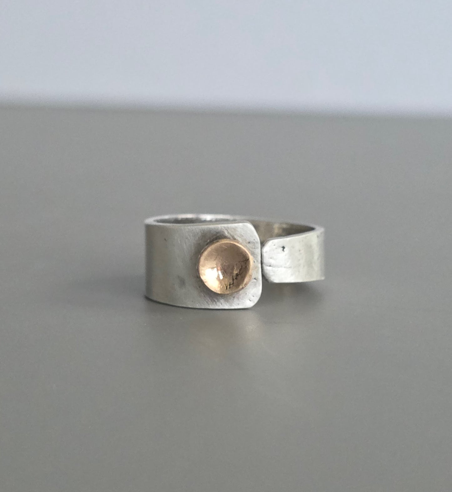Silver ring with a gold accent on a gray background