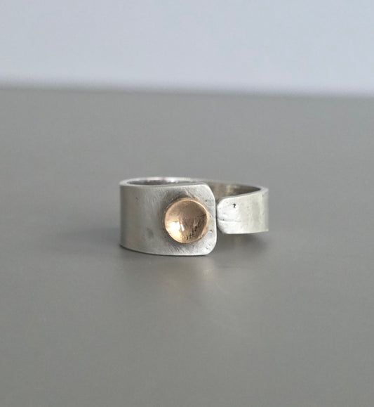 Silver ring with a gold accent on a gray background