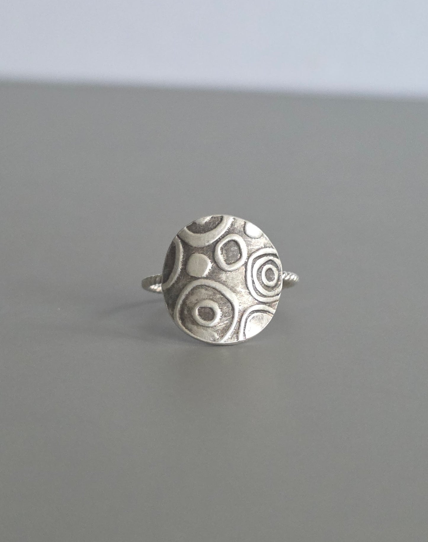 Silver ring with circular pattern on a gray background