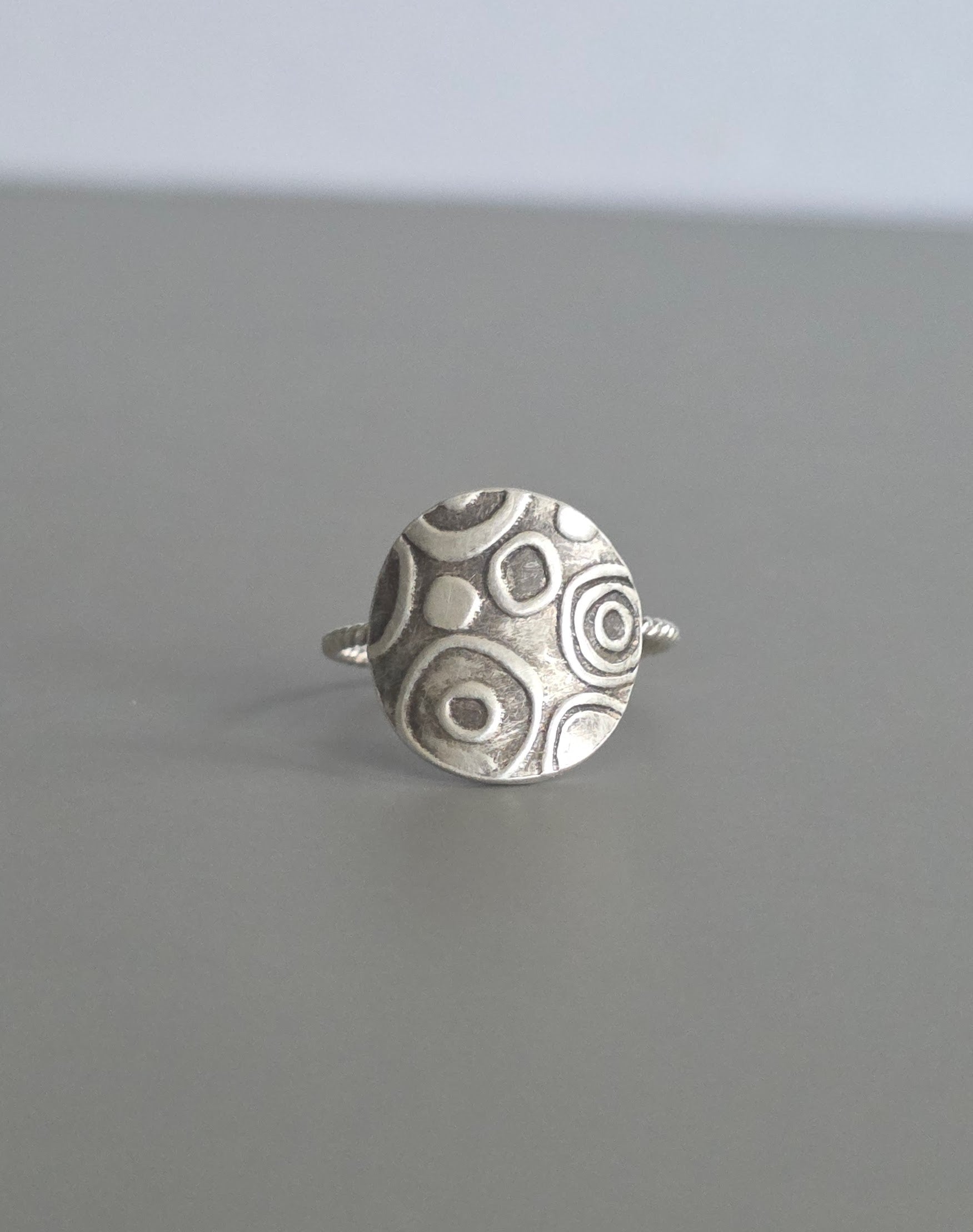Silver ring with circular pattern on a gray background