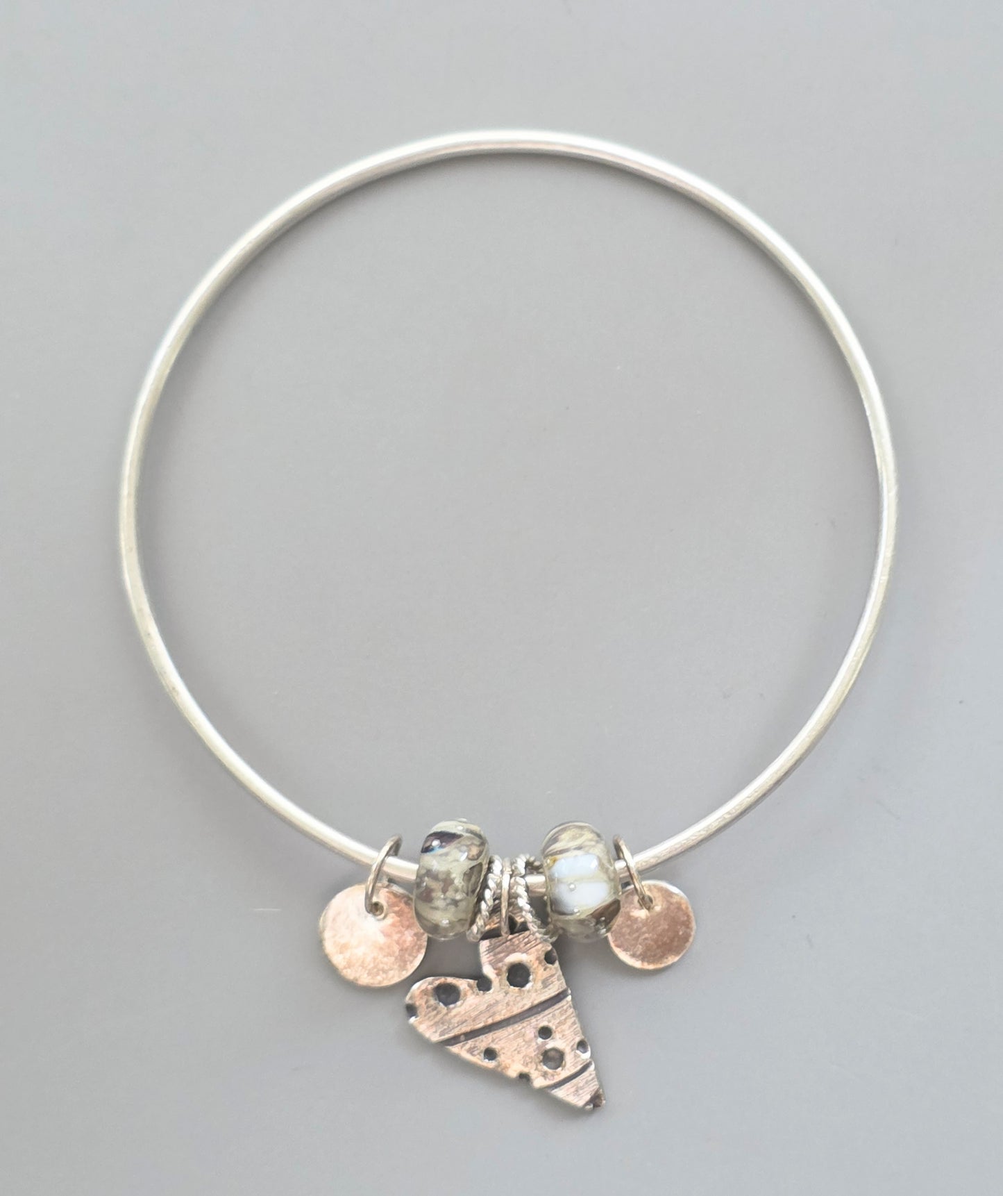 Silver bracelet with heart-shaped charm and beads on a gray background