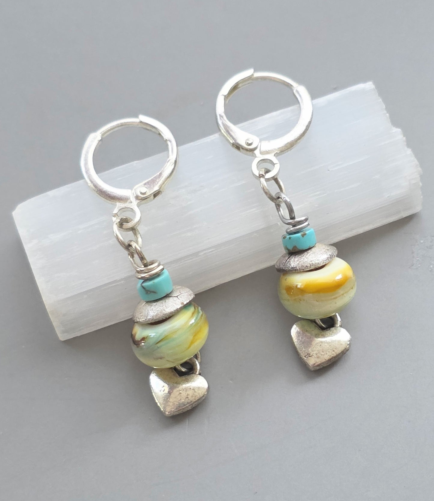 Pair of earrings with beads and heart charms on a light gray background