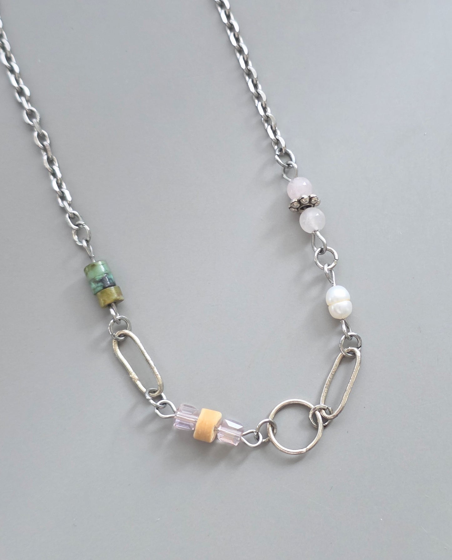 Necklace with various beads and links on a gray background