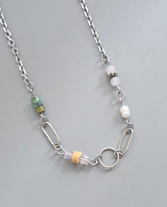 Necklace with various beads and links on a gray background